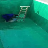 Worker applying green lining inside a tank