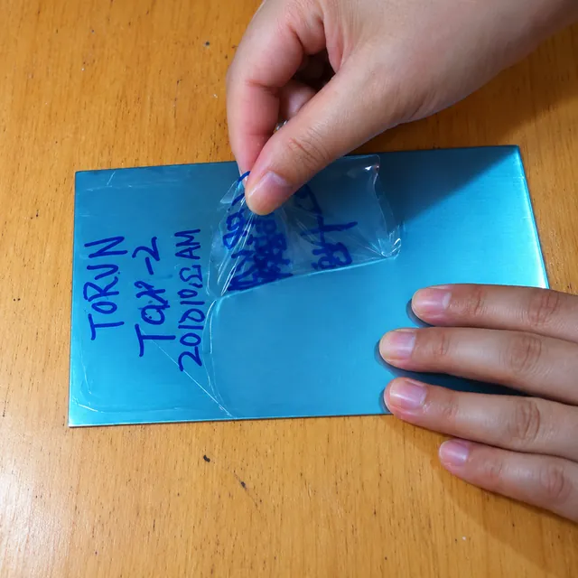 Clear coating being peeled from a blue test panel
