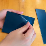 Flexible film being peeled from a blue panel