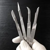 Gloved hand holding metal scalpel handles
