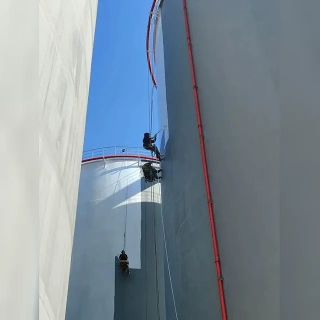 Worker applying a protective coating to a large storage tank