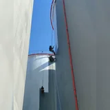 Worker applying a protective coating to a large storage tank